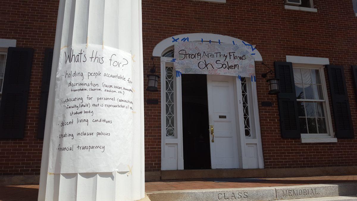 Protest organizers posted a banner with student grievances written all over it above the front entrance to Main Hall and a sign on one of the building's columns listing aspects for which protesters are advocating a change.